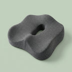 Coussin d'assise coccyx gris en mousse à mémoire de forme, vu de trois-quarts, avec son ouverture centrale